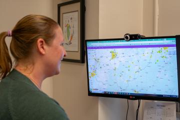 Natalie Kruse is shown looking at a computer screen that has air quality information on it
