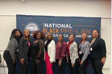 Students pose in front of a National Black Pre-Law Conference banner