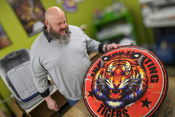 Sean Daniel is shown in his business working with a logo that features a Tiger