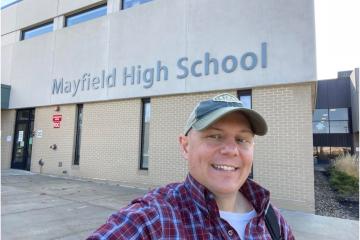 Man in baseball cap takes selfie outside Mayfield High School