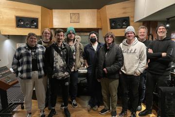 A group of students pose for a photo in a wood-paneled music studio