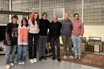 A group of students pose for a photo in a large music studio
