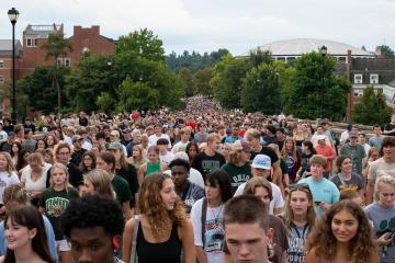 Many Ohio University First-year students walk across a bridge.