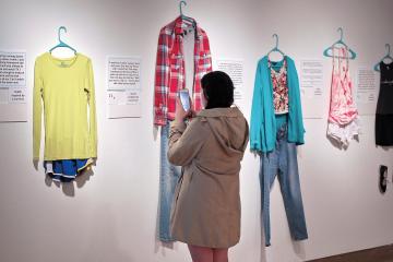 Student takes photos of clothing in an art gallery