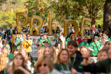 OHIO students carry balloons that spell out PRIDE during a parade at Ohio University