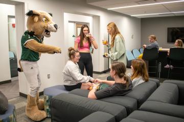 OHIO students, Rufus and community members relax in a lounge in The Den