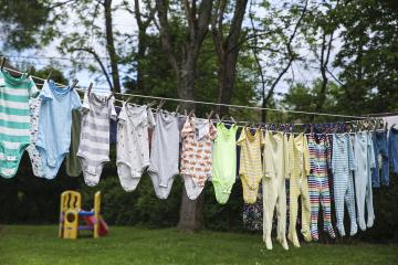 Various baby onesies on an outdoor clothes line.