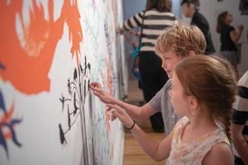 children touching interactive art pieces on the wall 