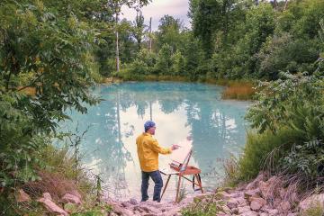 John Sabraw painting on a canvas by a pond