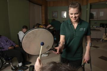 A music therapist assists a patient using a drum