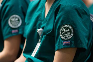 OHIO School of Nursing students wearing green scrubs with school patch on left shoulder.