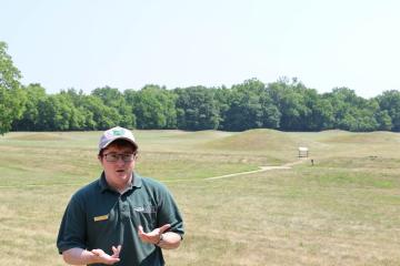 Johnathan Roberts stands in front of earthworks at Hopewell Culture National Historical Park