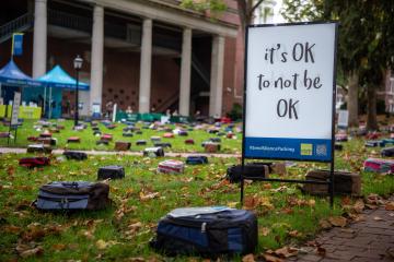 An image of the "Send Silence Packing" exhibit that displays backpacks on the ground.