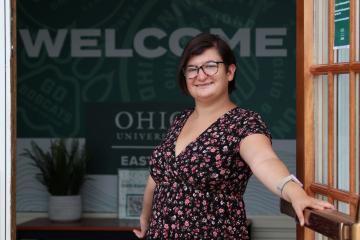 Women with short dark hair standing in front of a welcome sign