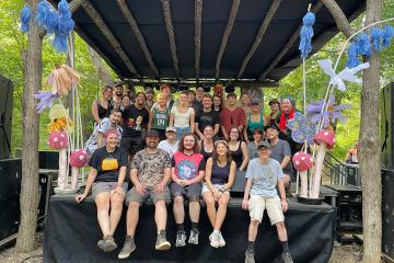 Ohio University faculty and students from the School of Media Arts and Studies pose with staff from OHD Studios on Nelsonville Music Festival's Creekside Stage.