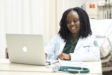 An OHIO nursing student working on a laptop in a medical setting. 