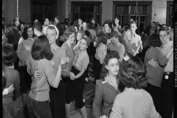 Old black-and-white photo of mixed-gender group of college students dancing in pairs