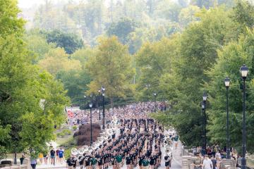 the Marching 110 leads a large group of students up Richland Avenue bridge