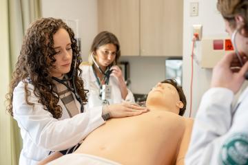 OHIO Physician Assistant program students honing their clinical skills using a medical simulation mannequin.