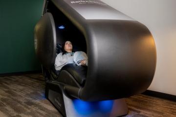 A student reclines in a large pod 