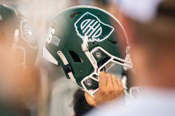 a hand grips a green Ohio University football helmet
