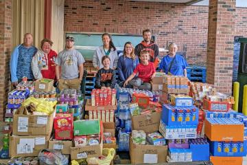community members stand behind pallet of food donation