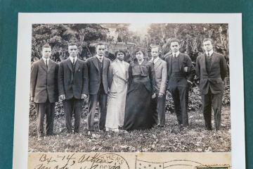 A black-and-white postcard of a group of people from the early 1900's