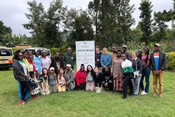 A group standing together in a forested area standing next to a sign that reads "Institue for Culture and Ecology."