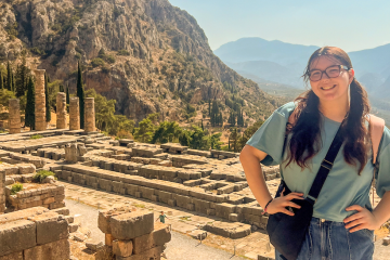 Student poses in front of ancient ruins in Greece