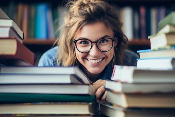 An image of a student smiling while surrounded by books