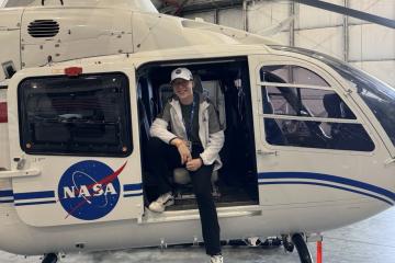 William Hamilton poses in a helicopter with a NASA logo on its side