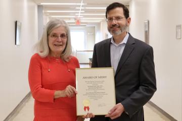Ann Rattine and David Rohall holding award of merit certificate