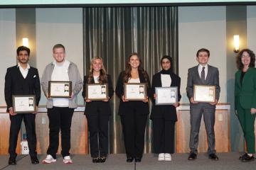 OHIO students Avery Murdock, Kiley Scanlon, Nathan Jennings, Espen Elliot, Manar Al Ghailani, and Mazin Al Jahwari hold their winners certificates while they pose for a photo with Kim Jordan.