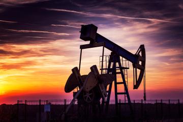 An oil derrick in front of a sunset.