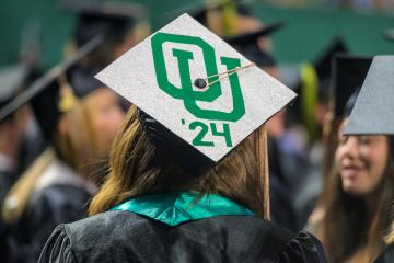 An OHIO graduate wears a cap that says OU '24 at Commencement