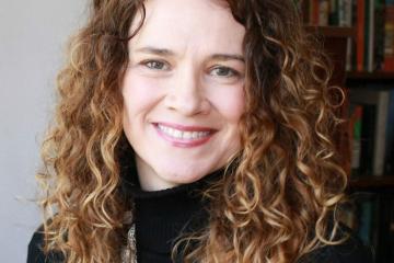A headshot of a woman with light, curly hair smiling.