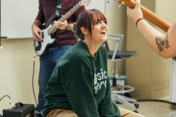 OHIO music therapy students playing together with guitar, bass and cajon.
