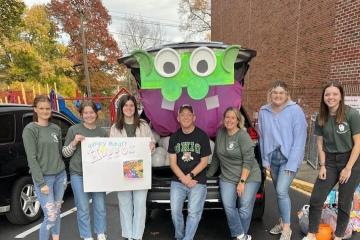 Members of the Student Social Work Association stand next to car that is decorated for Trunk or Treat