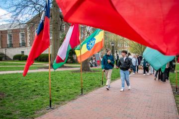 OHIO students and community members walk by the international flags on the College Green during the International Street Fair