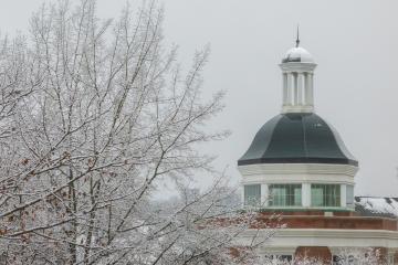 An OHIO building is shown next to a tree covered in ice and snow on a winter's day at Ohio University