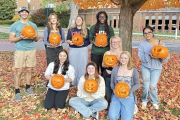Learning Community students hold jack-o-lanterns outside on a fall day at Ohio University