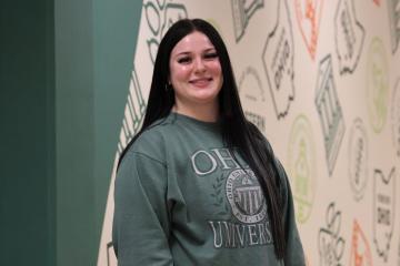 Female student with long black hair wearing a green sweatshirt 