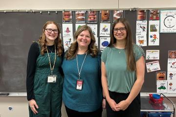 3 female teachers posed in front of blackboard in classroom