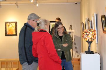 Three people look at a hand-crafted lamp in the art gallery at OHIO Chillicothe