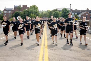 Marching 110 band members march up a brick street holding their instruments