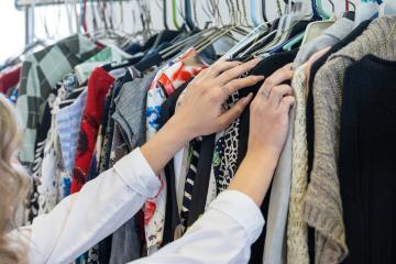 An individual looks through a rack of clothing items