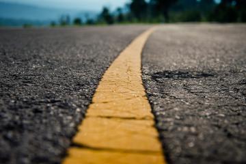 A close up of a generic roadway with the yellow line in the middle. 