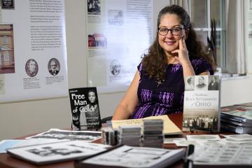 andrea Frohne sits at a table surrounded by artifacts from the African American Research and Service Institute