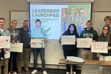 Members of Leadership Launchpad holds up signs about Leading