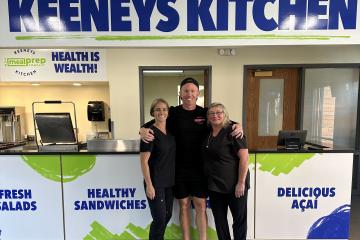 Three people dressed in black below sign reading Keeneys Kitchen